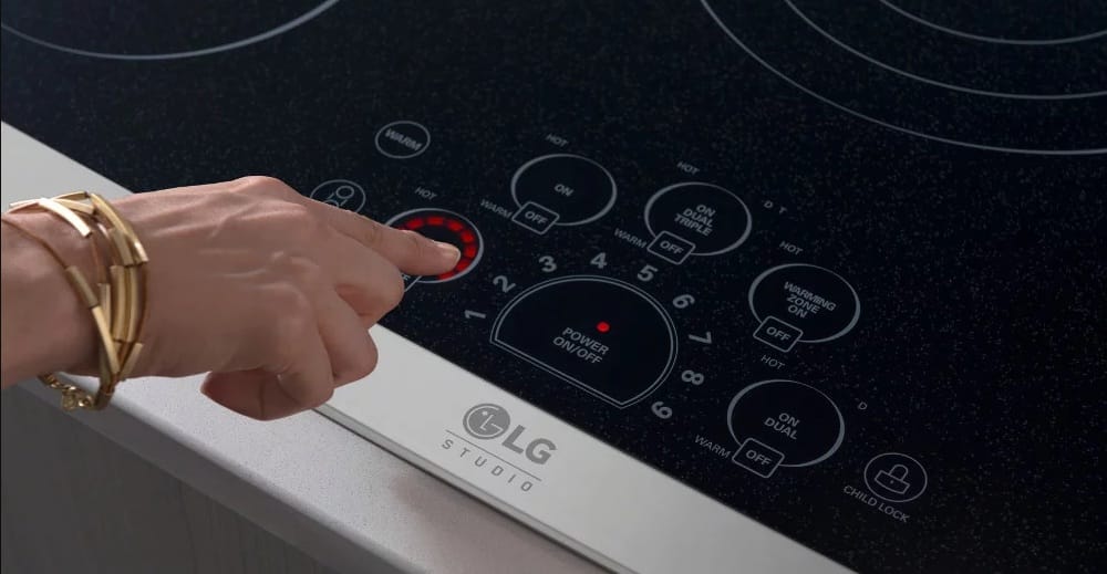 someone operating the touch controls on an LG Studio induction range cooktop