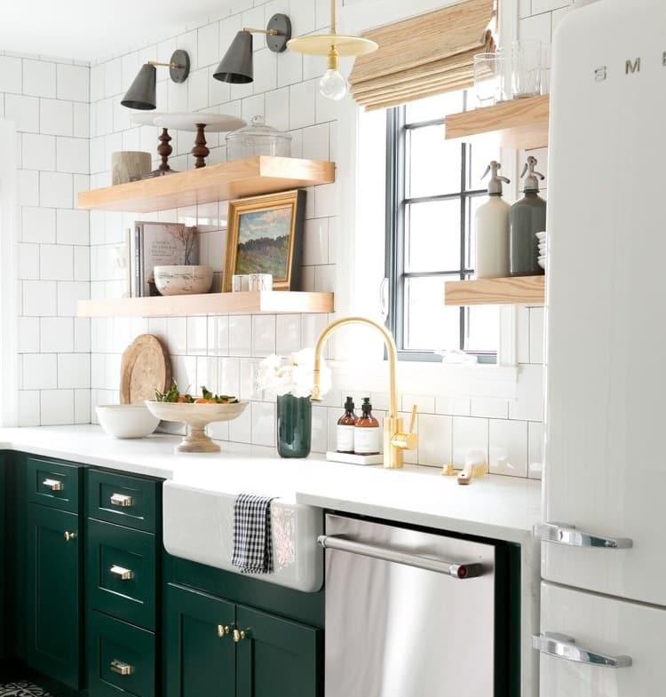 remodeled kitchen with white subway tile and mixed materials throughout - light wood, white solid surface counters, gold fixtures, stainless steel appliances, and forest green cabinets