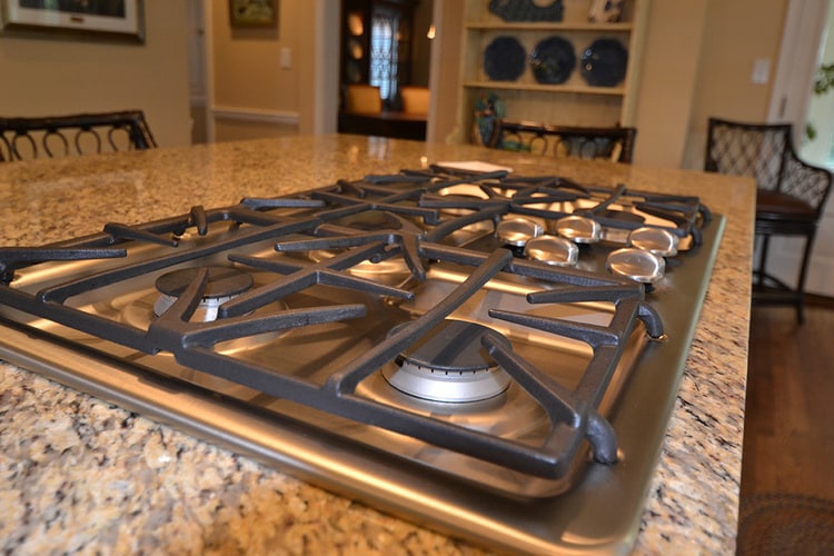 gas stove cooktop built into kitchen island with granite countertops