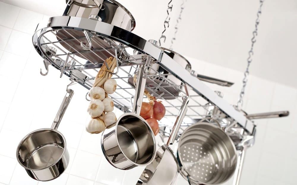 stainless steel potrack with pots, pans, garlic, and onions hanging from it