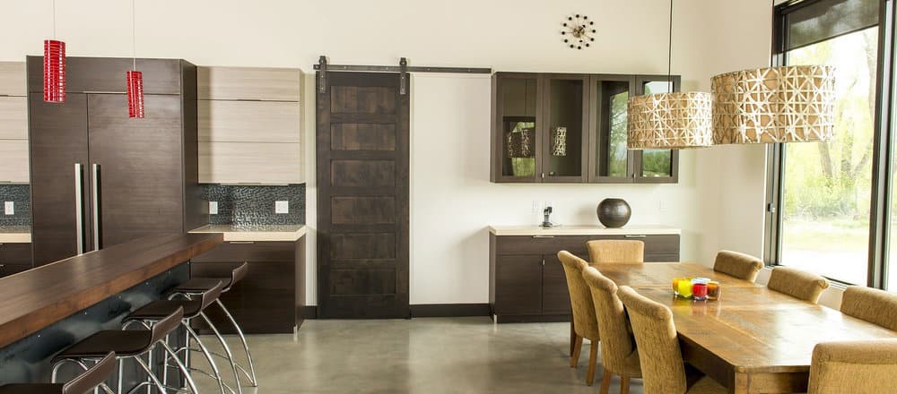 remodeled kitchen with two-toned cabinetry, wood tones throughout, and a dark wood sliding barn door