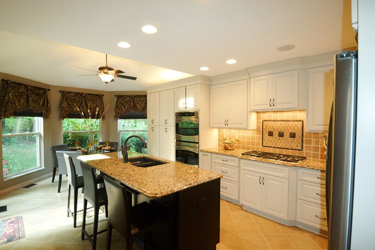 kitchen remodel with white cabinets, earth tone tile floors and backsplash, with granite countertops